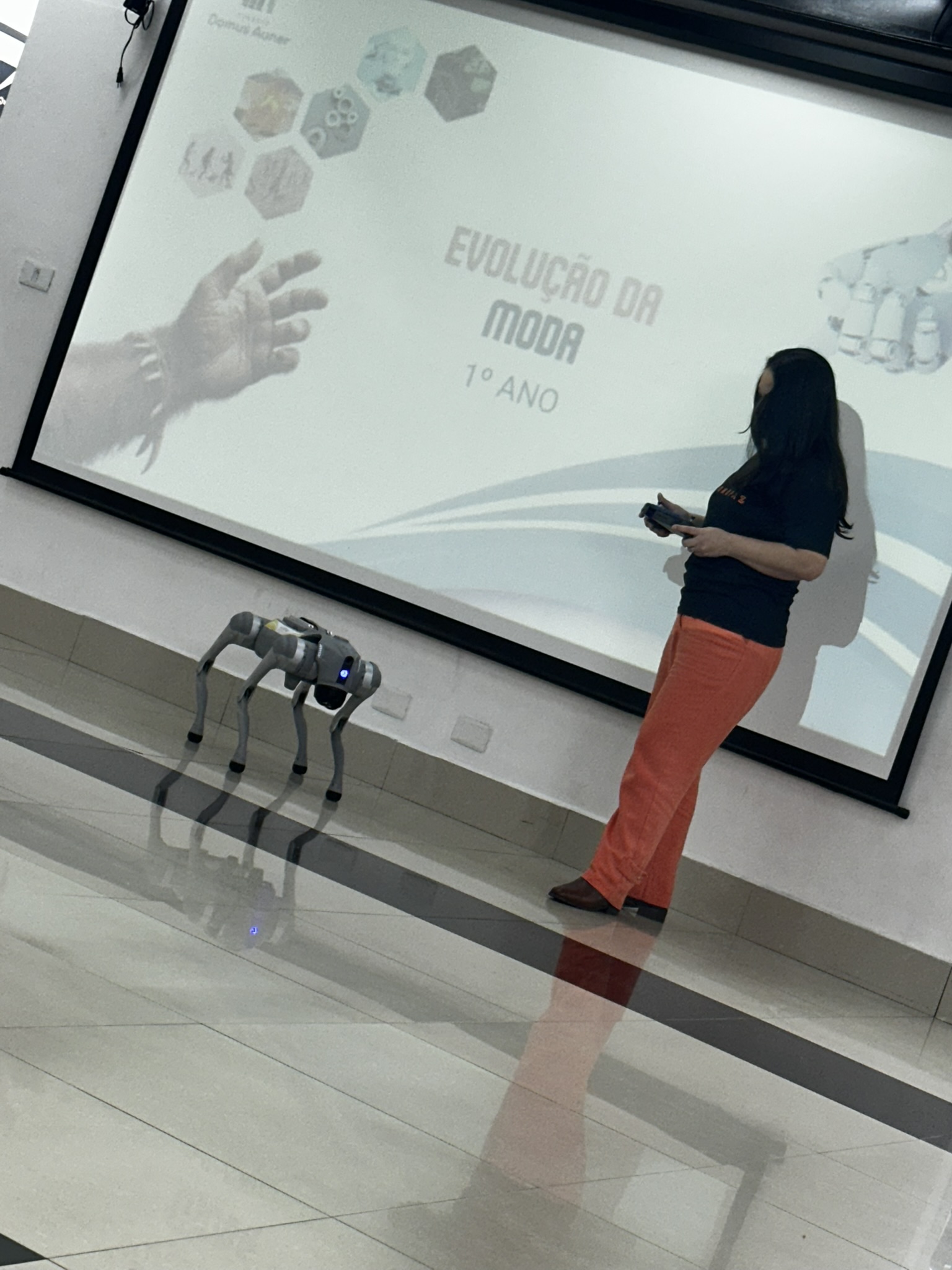 Operadora da RoboFaz conduzindo o cão robô durante uma apresentação em sala de aula